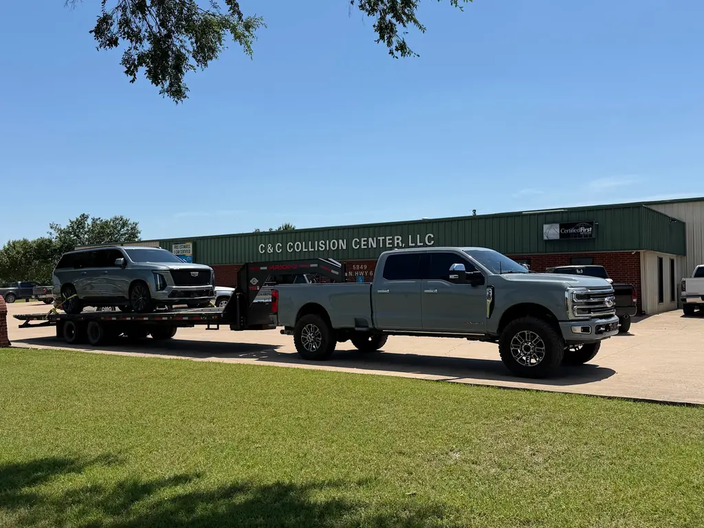 The C & C Collision Center building on North Highway 6 with a dually pickup and gooseneck trailer on the apron
