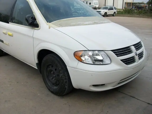 The finished white Dodge Caravan standing outside the C & C Collision Center building